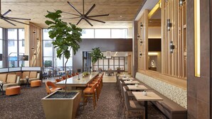 Un espacio interior amplio con una larga mesa de comedor, diversas opciones de asiento y una planta grande.