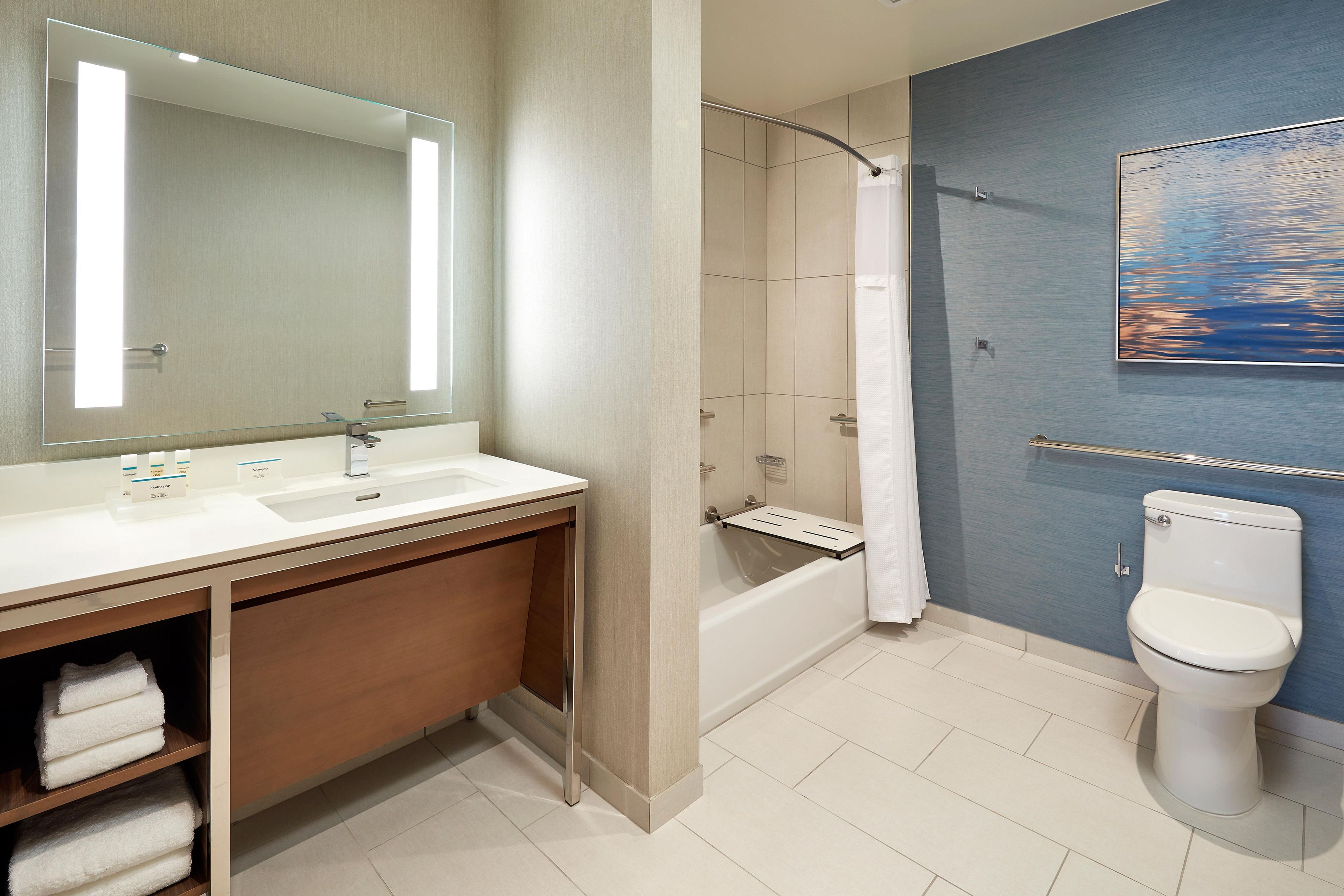 Ein modernes Badezimmer mit einem großen Spiegel, einer Badewanne, einer Toilette und einer Dusche.