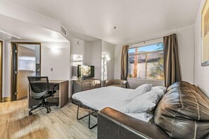 A hotel room with a bed, a desk with a chair, a television, and a window with curtains. - Hawthorn Suites by Wyndham Chandler/Phoenix Area (Chandler)