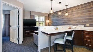 A modern kitchen with a bar area, a flat-screen TV, and a large window. - Residence Inn by Marriott Ann Arbor North (Ann Arbor)