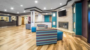 A spacious lobby with a wooden floor, a reception desk, a fireplace, and colorful seating areas. - Comfort Inn West Valley Salt Lake City South (West Valley City)