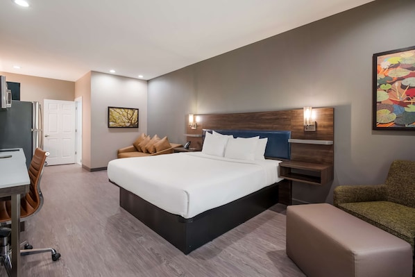 Una habitación de hotel moderna con una cama grande, un escritorio, una silla y un sofá.