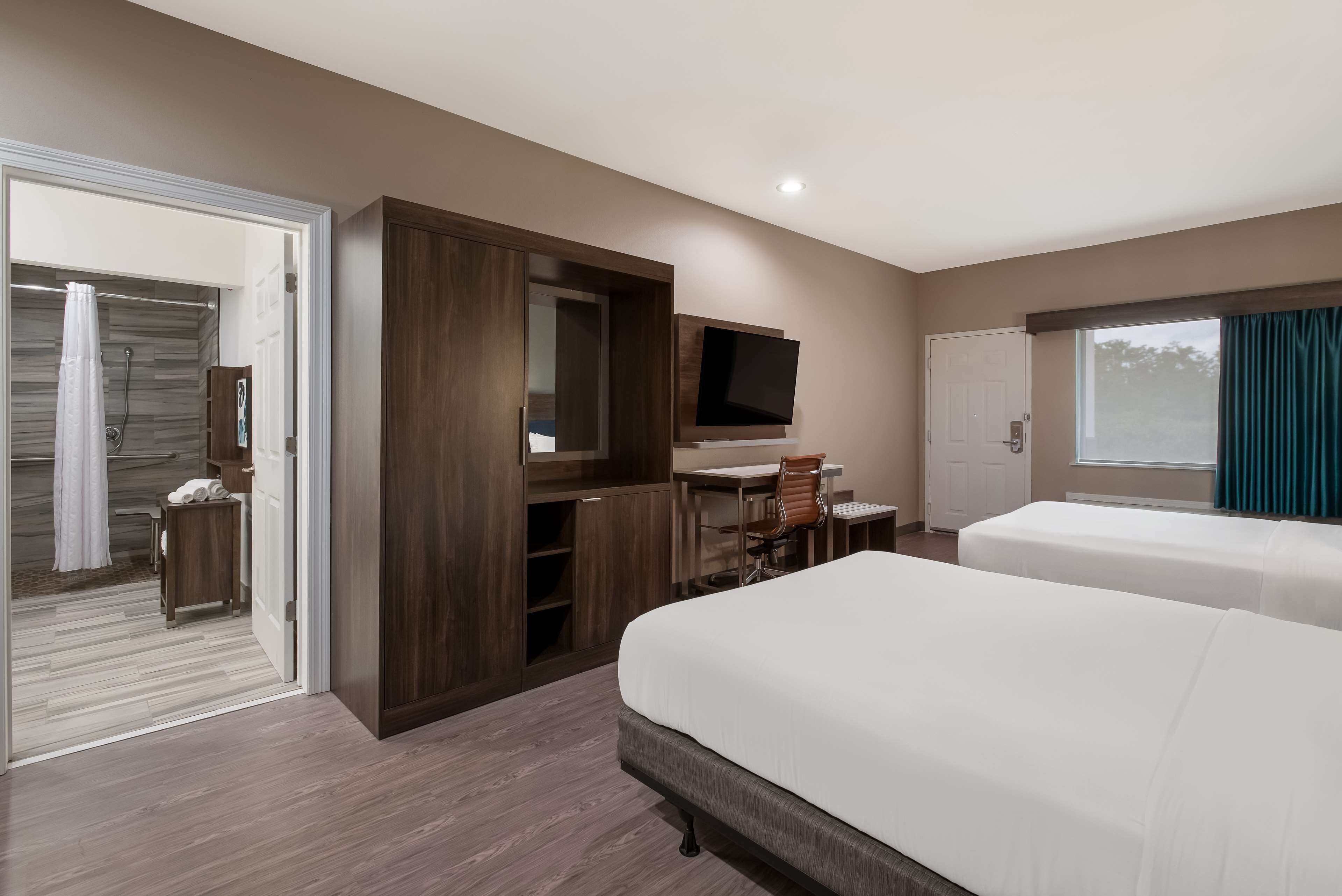 Une chambre d’hôtel dotée d’un grand lit, d’un bureau avec une chaise, d’un téléviseur fixé au mur et d’une porte coulissante donnant sur un balcon.