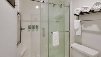 Une salle de bain moderne avec une douche à parois de verre, des toilettes et un porte-serviettes avec des serviettes pliées.