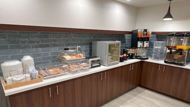 Une cuisine moderne équipée d’un bar pour prendre le petit-déjeuner, d’une machine à café et d’un réfrigérateur.