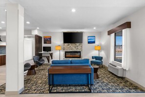 A modern living room with a fireplace, blue sofa, and a flat-screen TV.