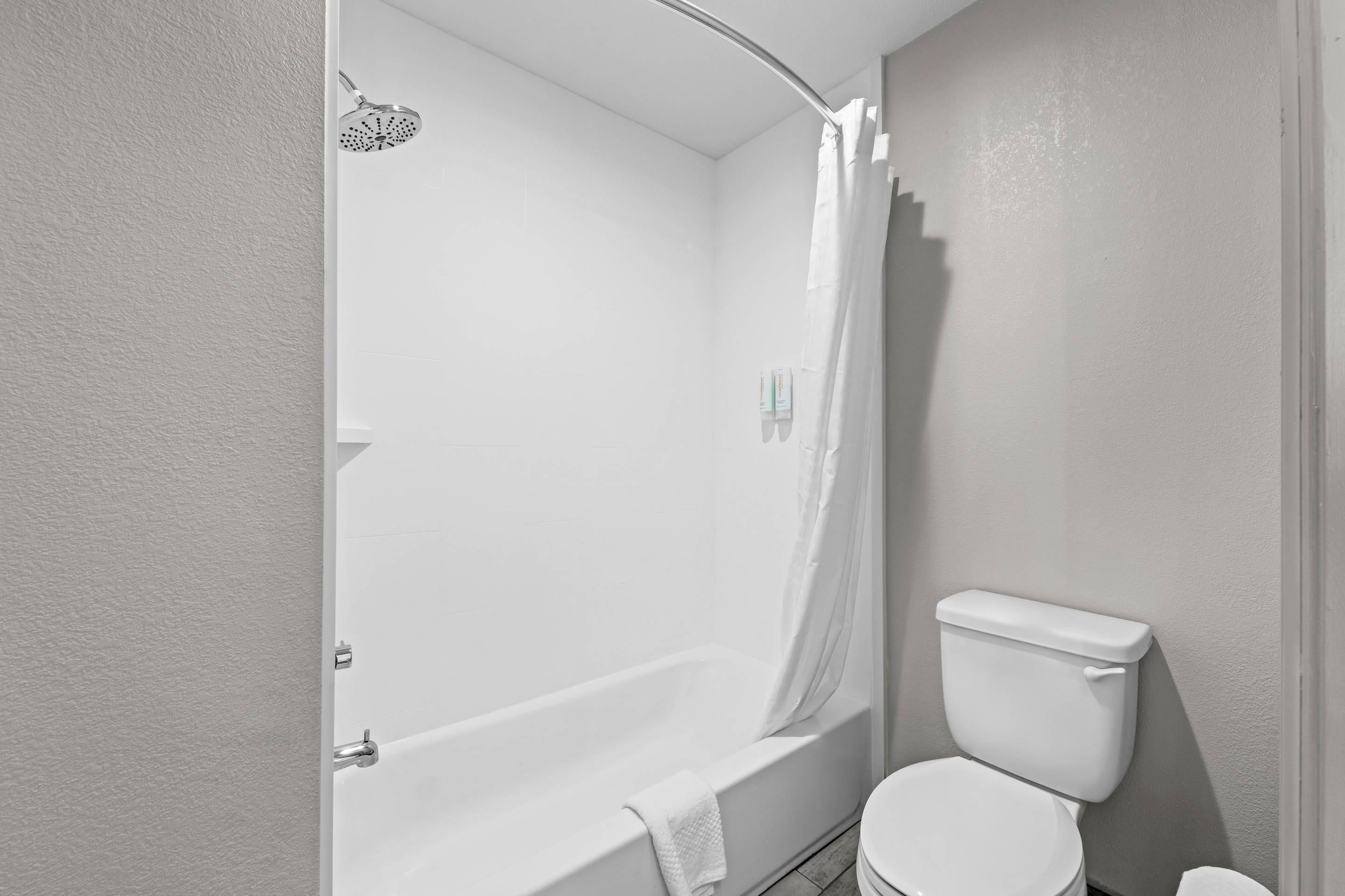 Un baño con bañera, inodoro y cortina de ducha.