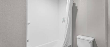 Un baño con bañera, inodoro y cortina de ducha.