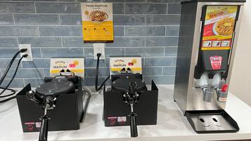 Estación para hacer gofres con dos planchas para gofres, un letrero que dice Golden Waffles y un dispensador de porciones.