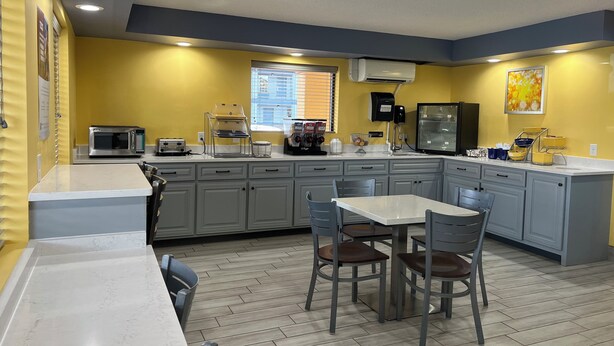 A compact kitchen with a microwave, toaster, and coffee maker, featuring grey cabinets and a wooden floor. - Days Inn & Suites by Wyndham Warner Robins Near Robins AFB (Warner Robins)