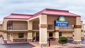 A Days Inn & Suites with a red roof, beige walls, and a sign with a sun emblem. - Days Inn & Suites by Wyndham Warner Robins Near Robins AFB (Warner Robins)