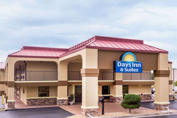 A Days Inn & Suites with a red roof, beige walls, and a sign with a sun emblem. - Days Inn & Suites by Wyndham Warner Robins Near Robins AFB (Warner Robins)