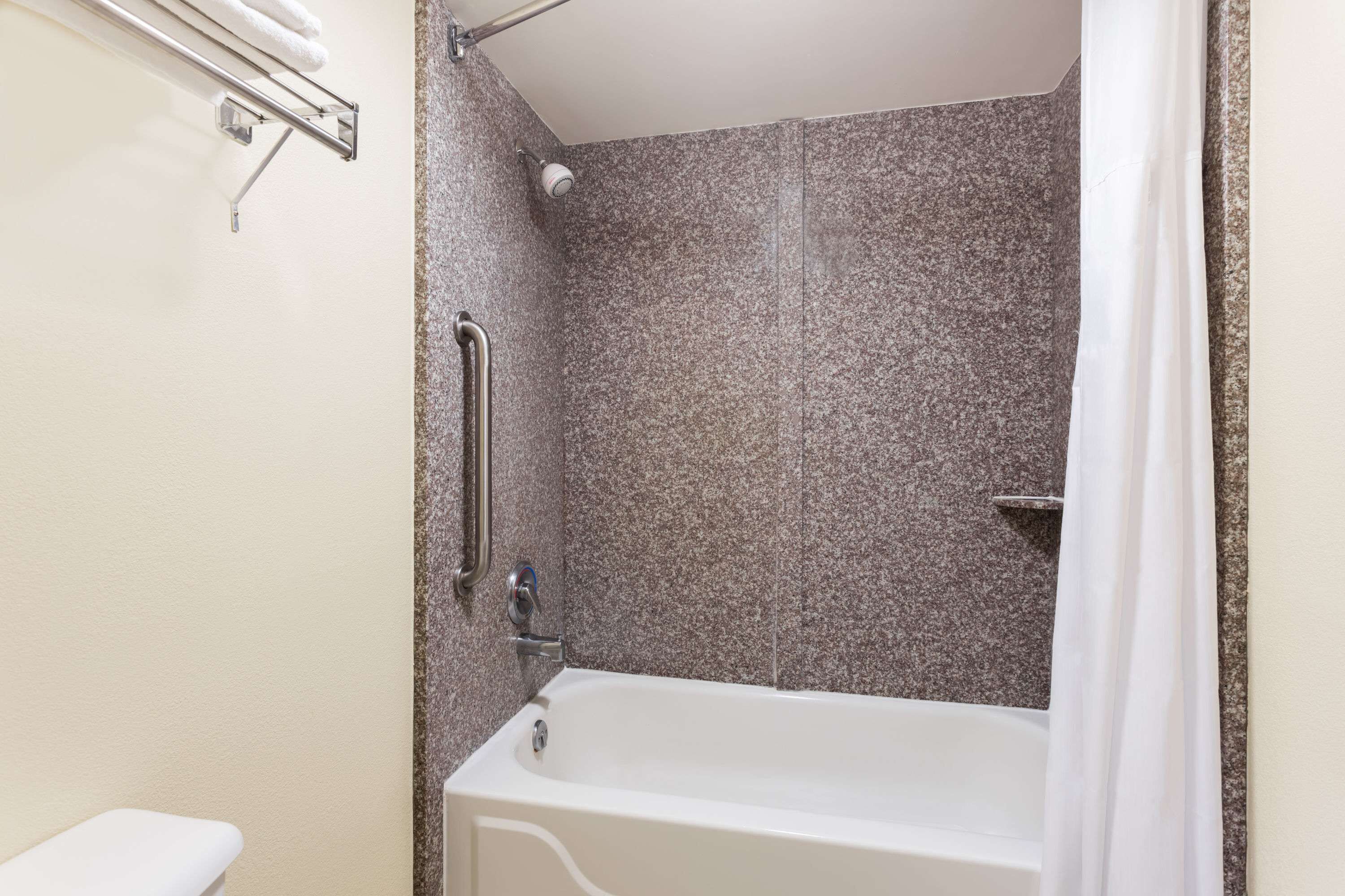 Un baño con bañera, ducha y barandilla.