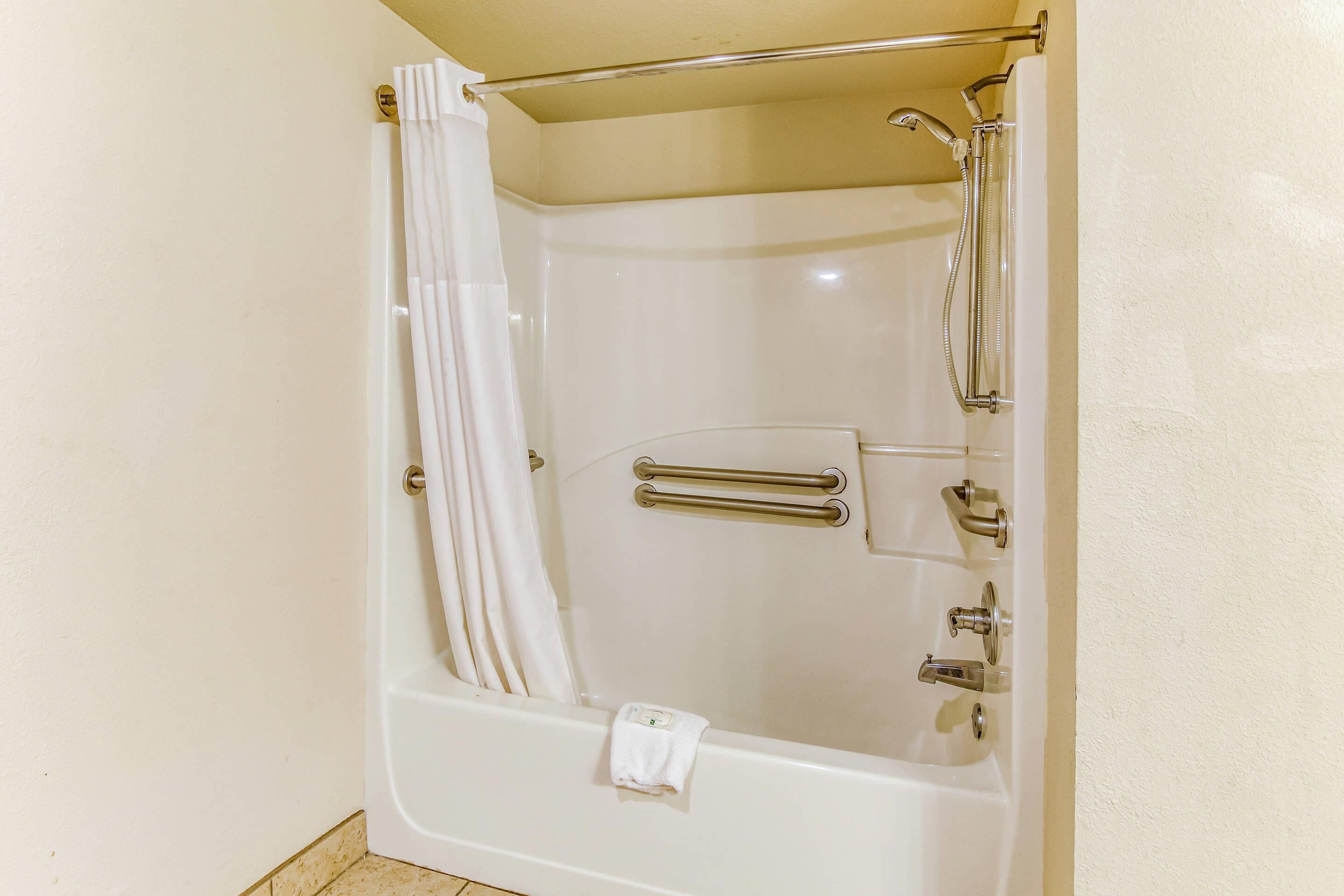 Eine weiße Badewanne mit Duschkopf, Handtuchhalter und einer flexiblen Duschbrause.