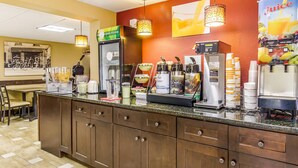 Ein Frühstücksbuffet mit Kaffeemaschine, Saftspender und Kühlschrank.