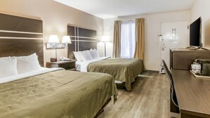 Ein Hotelzimmer mit zwei Betten, einem Schreibtisch, einem Fernseher und einer Minibar.