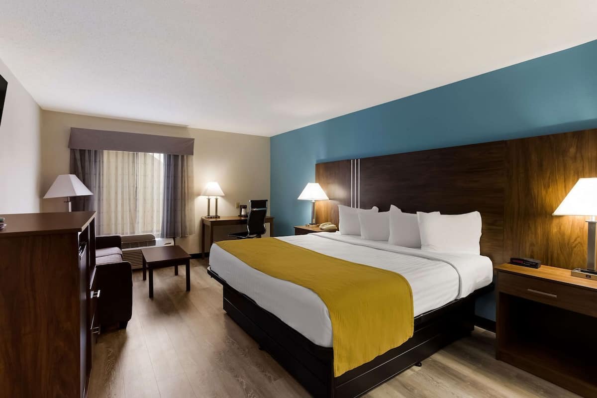 Une chambre d’hôtel équipée d’un lit, d’un bureau, d’une chaise et de tables de chevet.