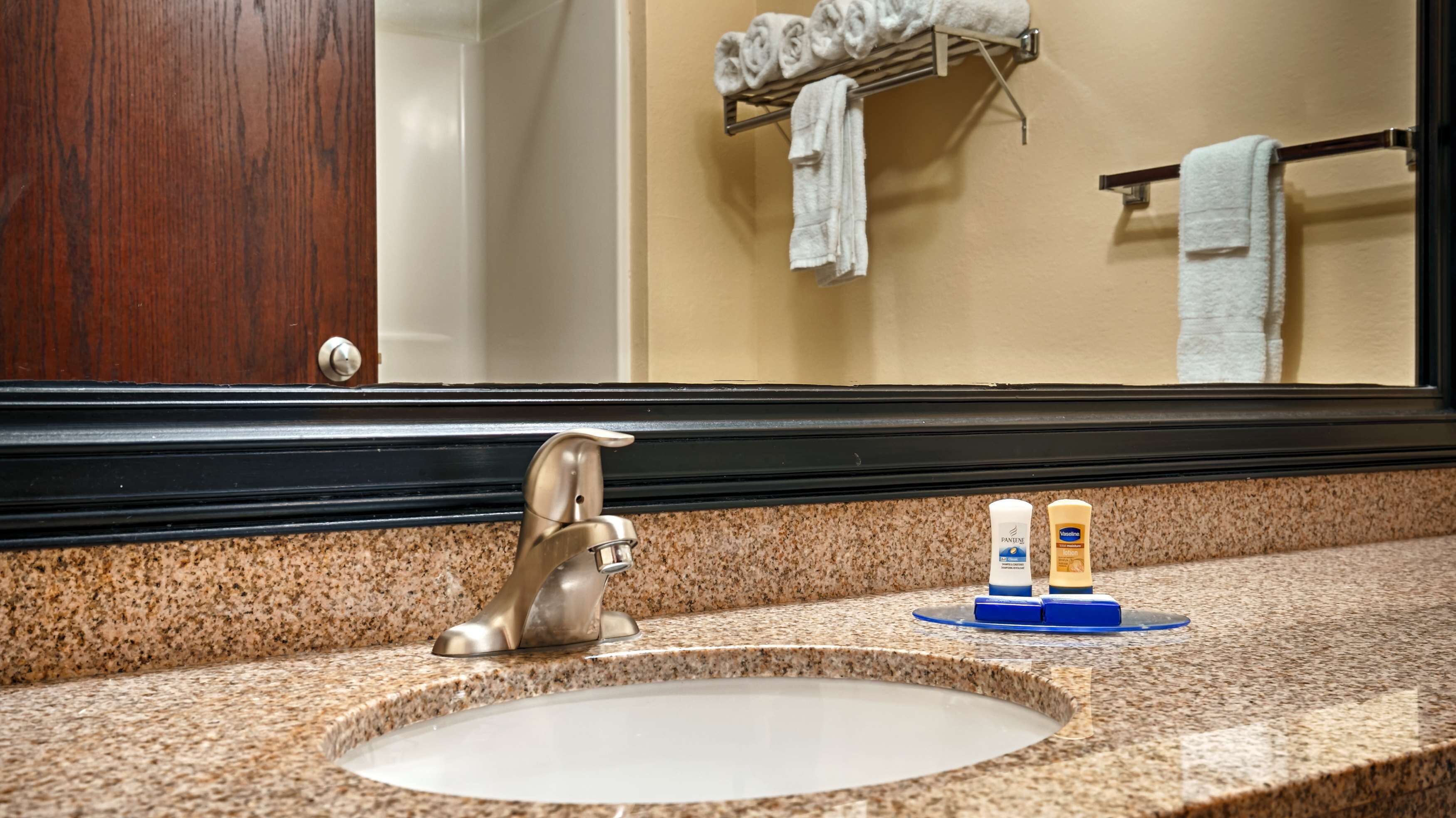 A bathroom sink with a granite countertop, a faucet, and two toiletry bottles on a soap dish.