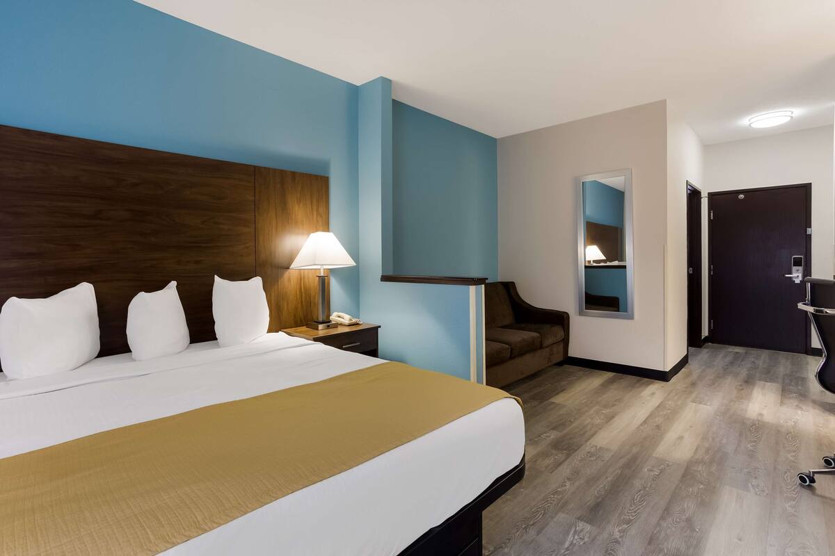 Une chambre d’hôtel avec un grand lit, un bureau avec une lampe, une chaise et un miroir.