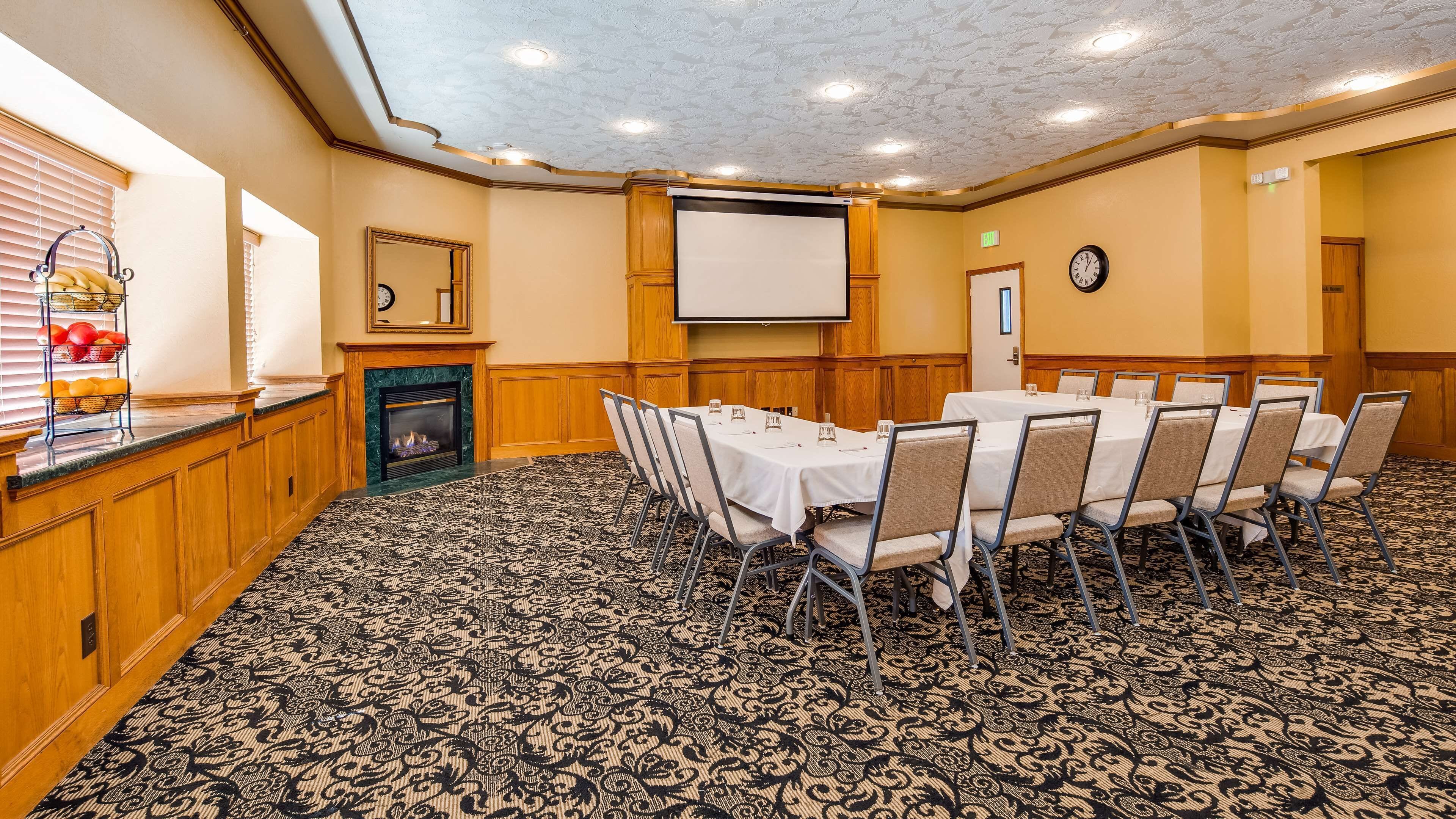 A conference room with a fireplace, a projector screen, and a clock on the wall.