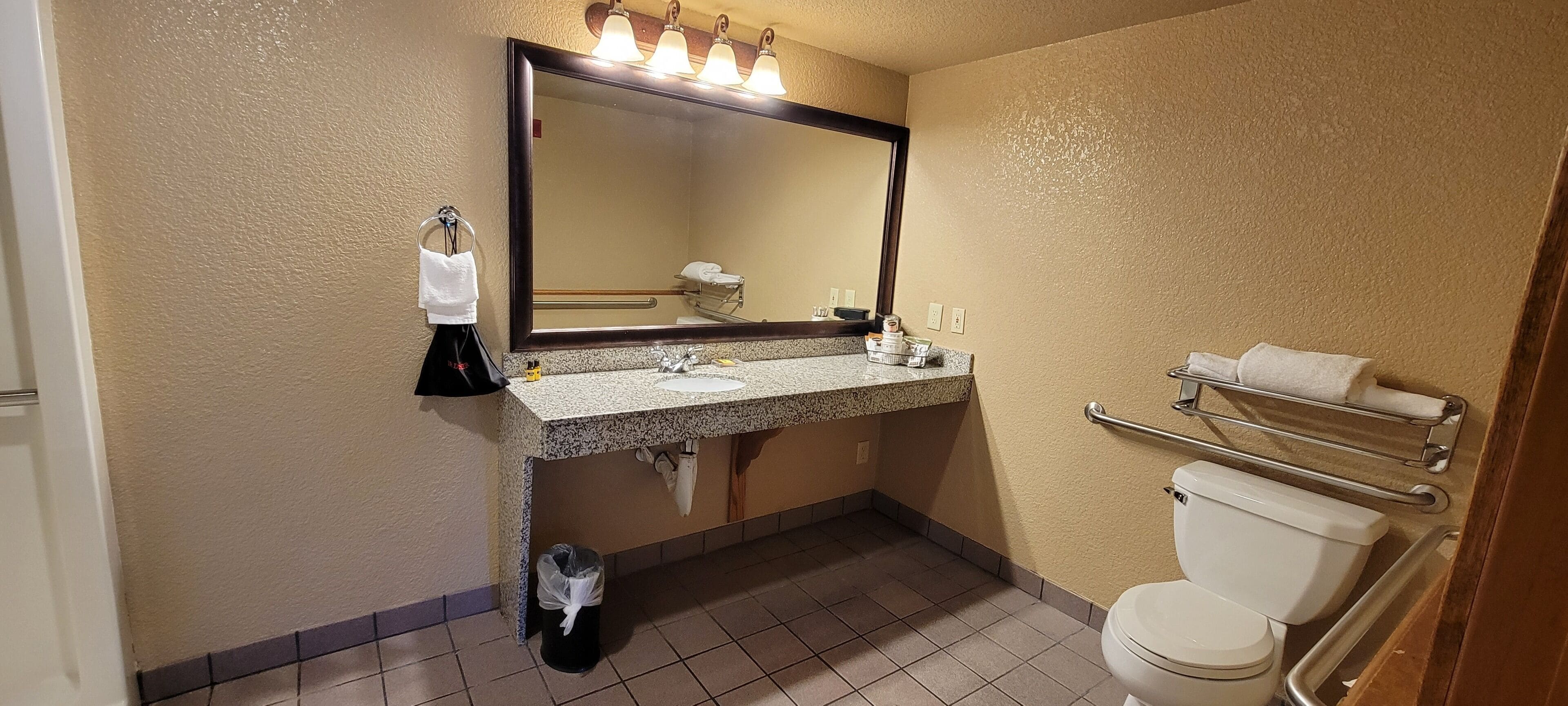 A bathroom with a sink, mirror, towel rack, and toilet.