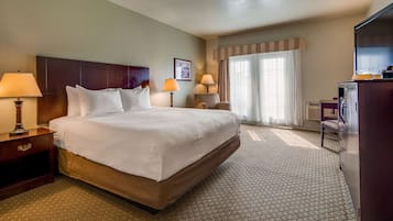 A hotel room with a large bed, two bedside tables with lamps, a wardrobe, and a window with curtains.