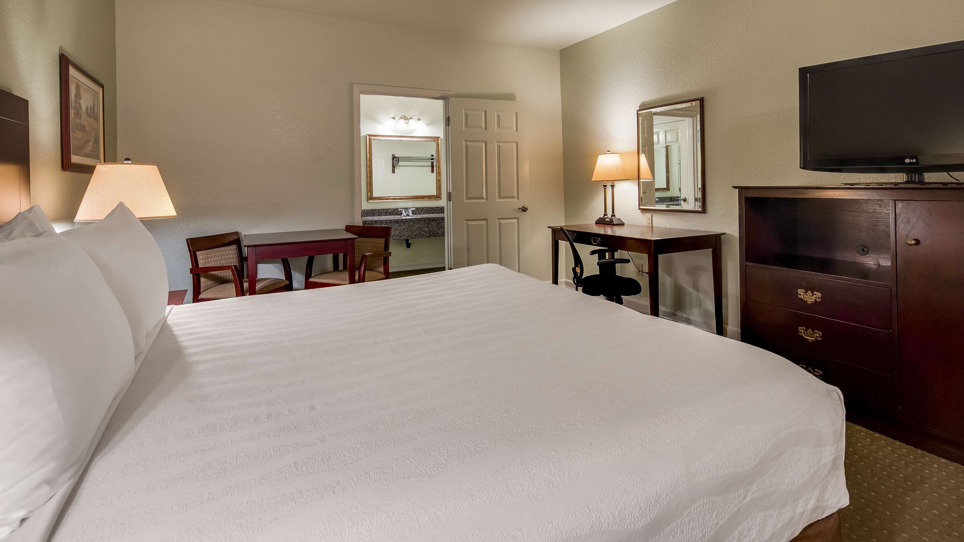 Hotelkamer met een groot bed, een bureau, een stoel, een kast, een televisie en een spiegel.