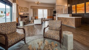 A modern hotel lobby with patterned chairs, a sofa, a fireplace, and artwork on the walls.