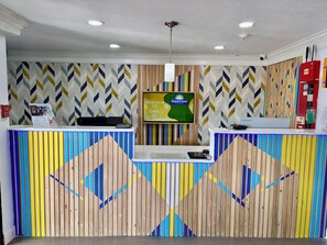 Un comptoir d’accueil doté d’un panneau numérique, d’un système d’alarme incendie et d’un décor mural en bois.
