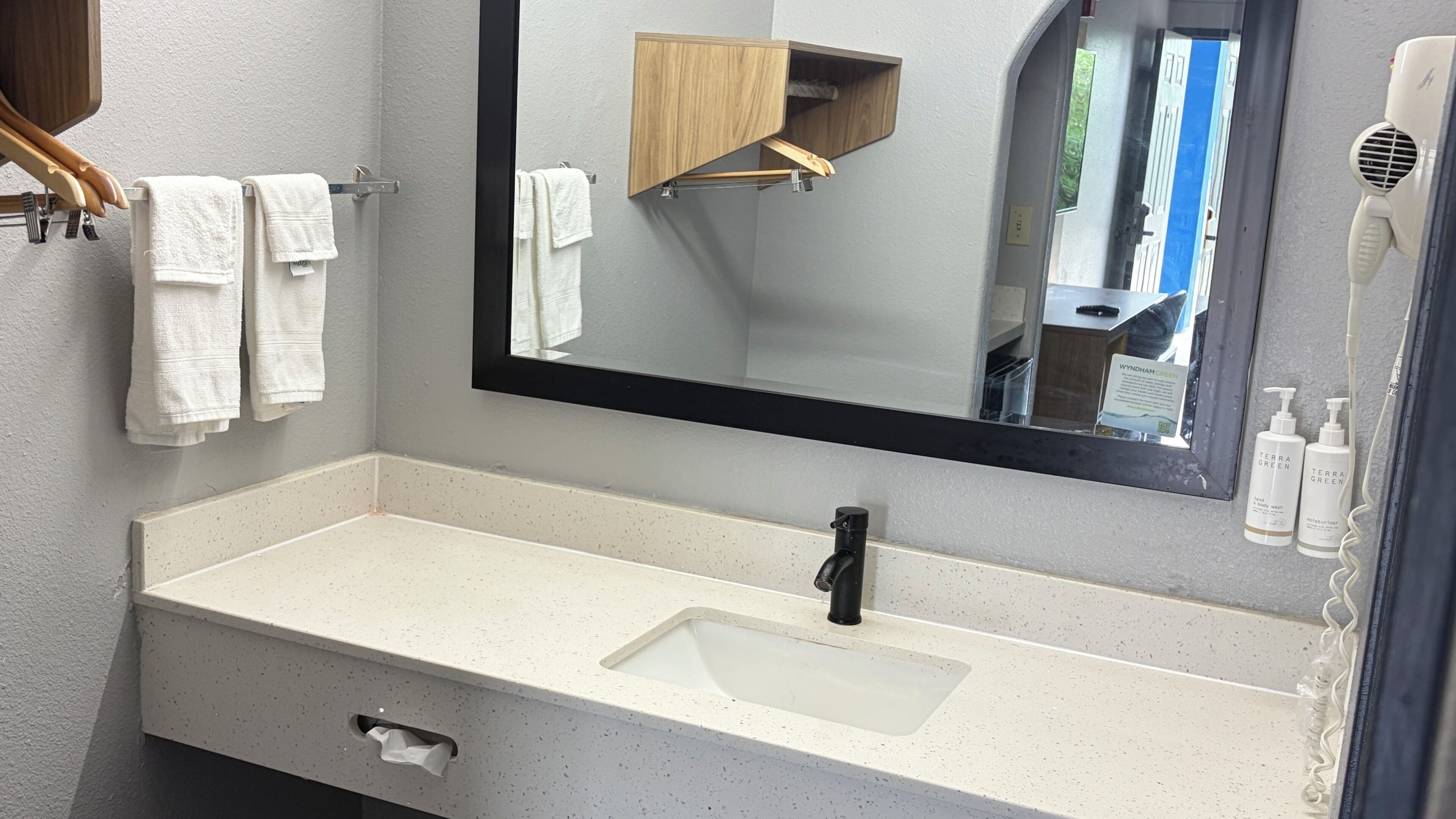 A bathroom with a white sink, a black faucet, a mirror, and a hairdryer.