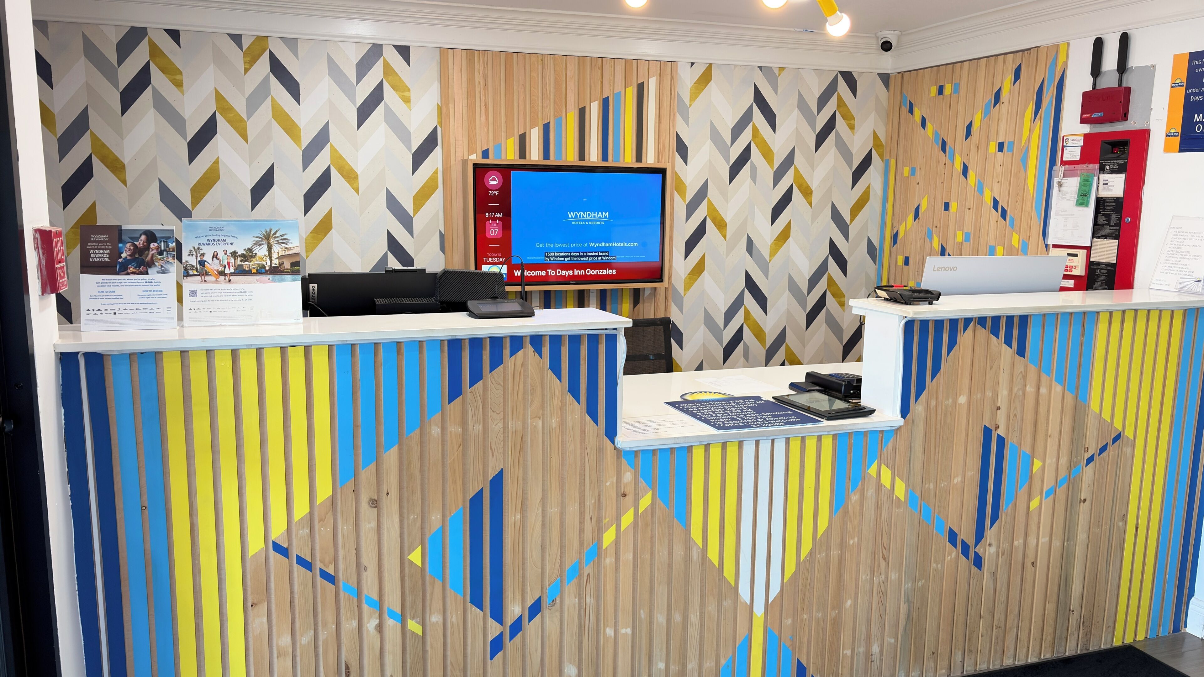 Ein Hotelrezeptionsschalter mit einem digitalen Bildschirm, einem Computer und einem Telefon.