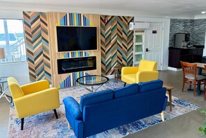 A living room with a blue sofa, yellow armchairs, a TV, and a fireplace. - Days Inn by Wyndham Gonzales (Gonzales)
