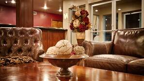 A leather sofa, a wooden table with a decorative bowl, and a floral arrangement in a room with wooden paneling and a red accent wall.