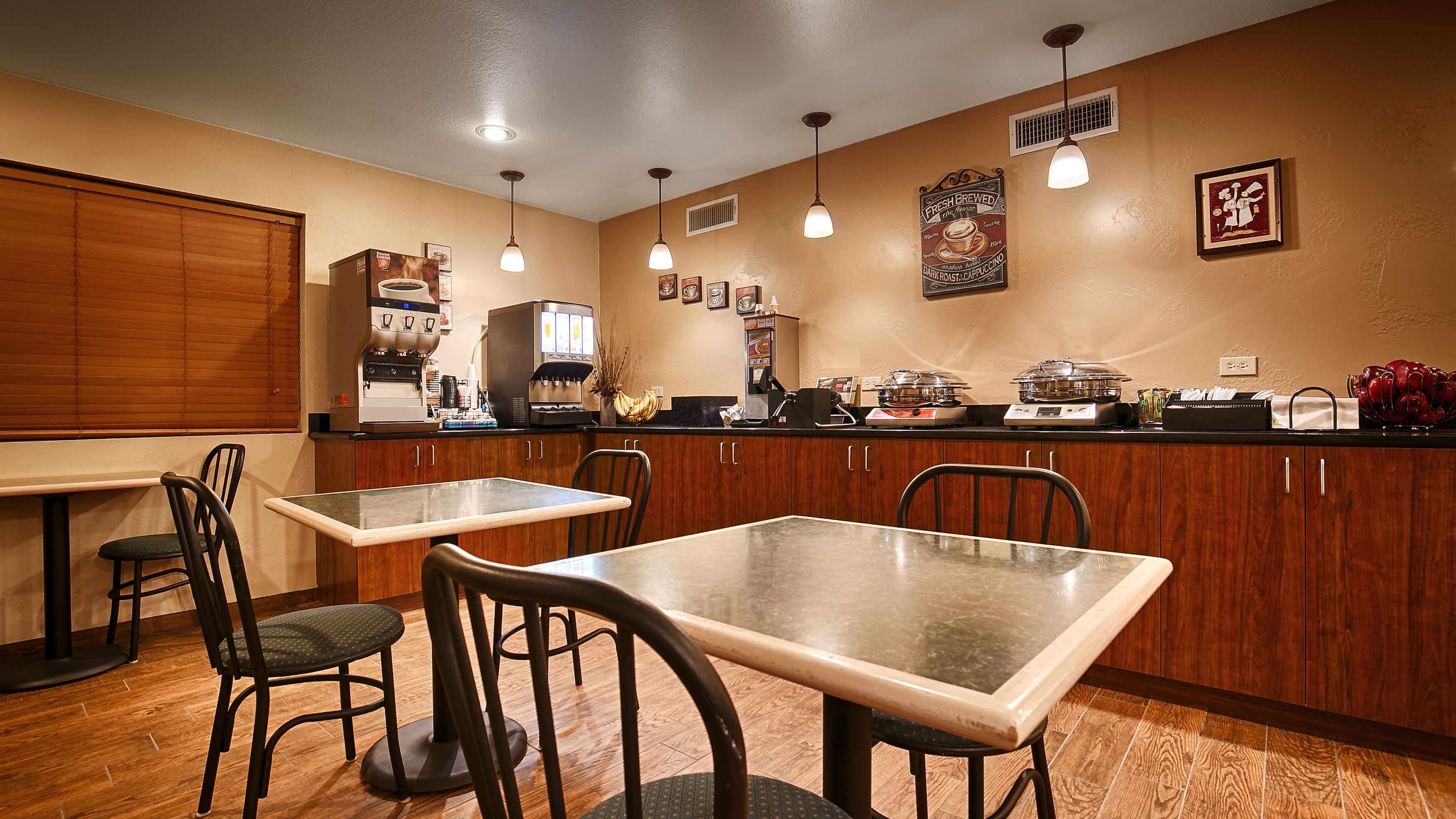 A kitchen with wooden cabinets, a coffee machine, and a dining area with a table and chairs.