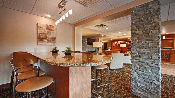 A hotel lobby with a bar area, seating, a stone accent wall, and a television. - Comfort Inn & Suites Copley Akron (Akron)