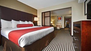 A hotel room with a large bed, a desk, a chair, a TV, and a door leading to another room. - Comfort Inn & Suites Copley Akron (Akron)