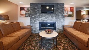 A modern living room with two sofas, a fireplace, a flat-screen TV, and a decorative bowl on a small table. - Comfort Inn & Suites Copley Akron (Akron)