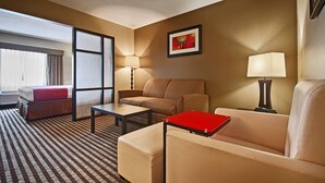 A hotel room with a bed, a sofa, a chair, a small table, and a desk with a laptop. - Comfort Inn & Suites Copley Akron (Akron)