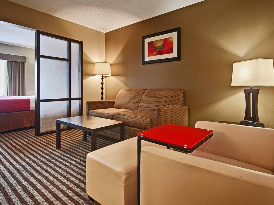 Ein Hotelzimmer mit Bett, Sofa, Sessel, einem kleinen Tisch und einem Schreibtisch mit einem Laptop.