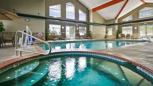 An indoor swimming pool with clear water, a lifeguard chair, and multiple exits.