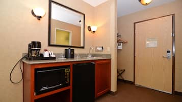 Baño de hotel pequeño con lavamanos, espejo y cafetera.