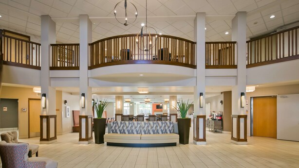A spacious lobby with a central seating area, high ceilings, and a wooden railing overlooking the space.