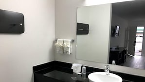 A modern bathroom with a black countertop, white sink, and a large mirror. - Motel 6 Metropolis, IL (Metropolis)