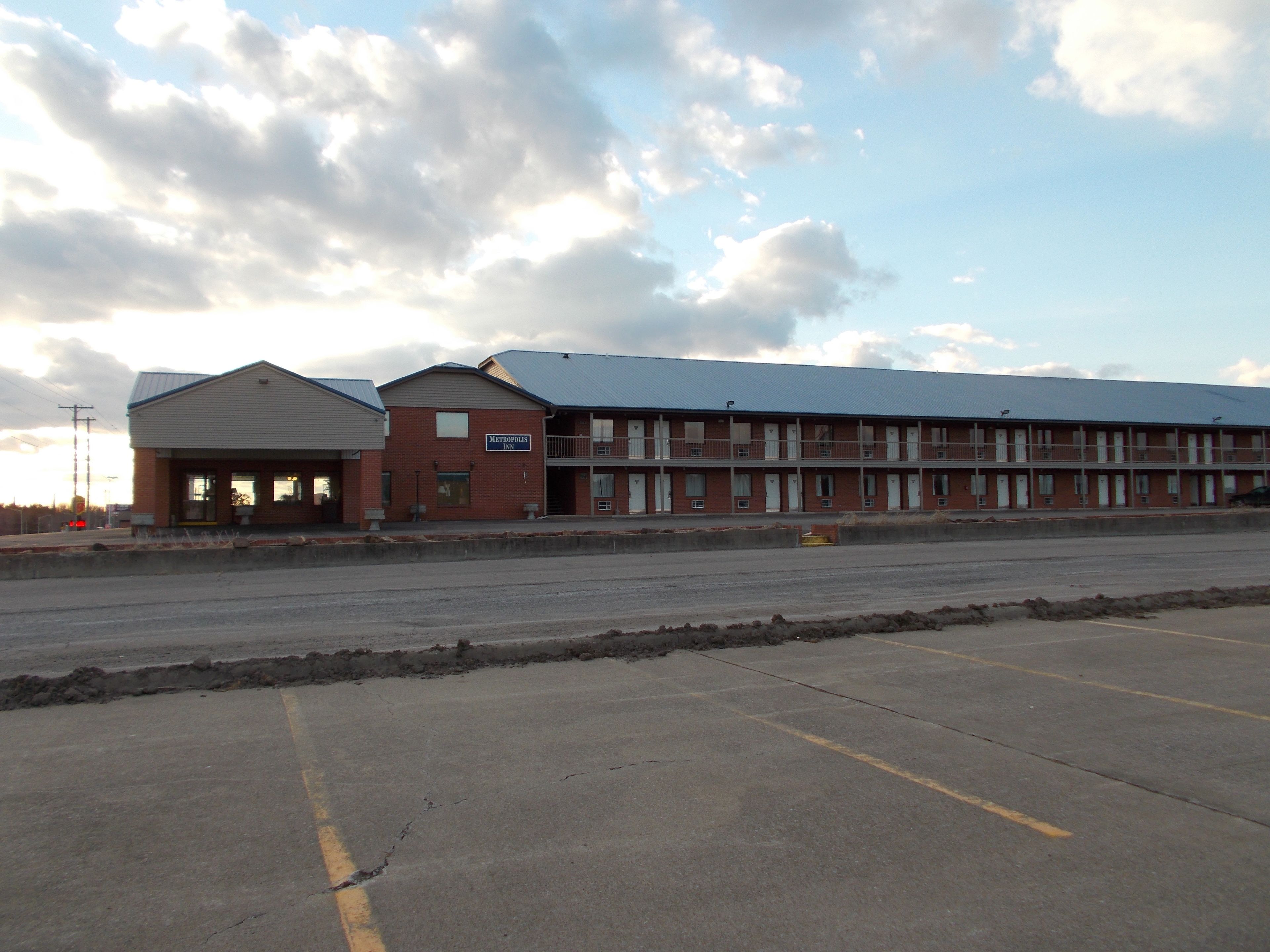 A motel with a two-story building, a covered parking area, and a large parking lot.