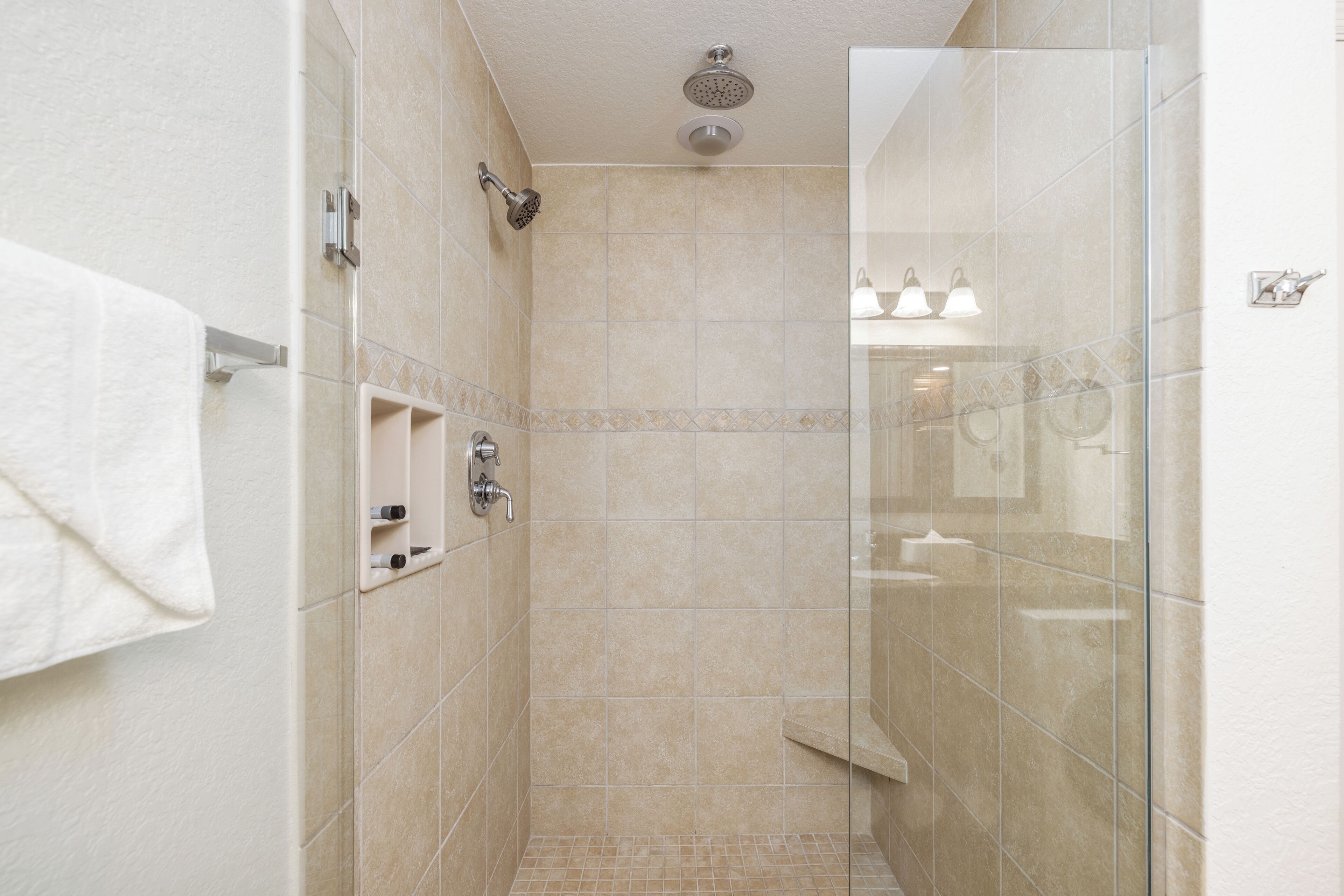 A walk-in shower with a glass door, a handheld showerhead, and a wall-mounted towel rack.