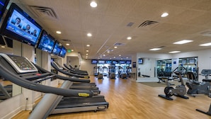 Un gimnasio con cintas de correr, bicicletas estáticas y máquinas de pesas.