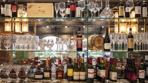 Zona de bar con varias estanterías que exhiben botellas de vino y copas.