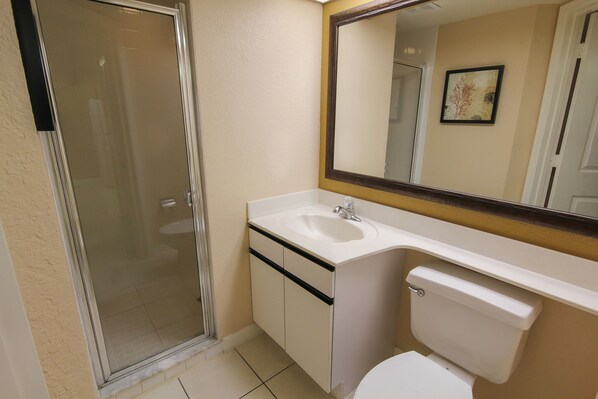 Une salle de bain avec une douche à parois de verre, un lavabo blanc et des toilettes.