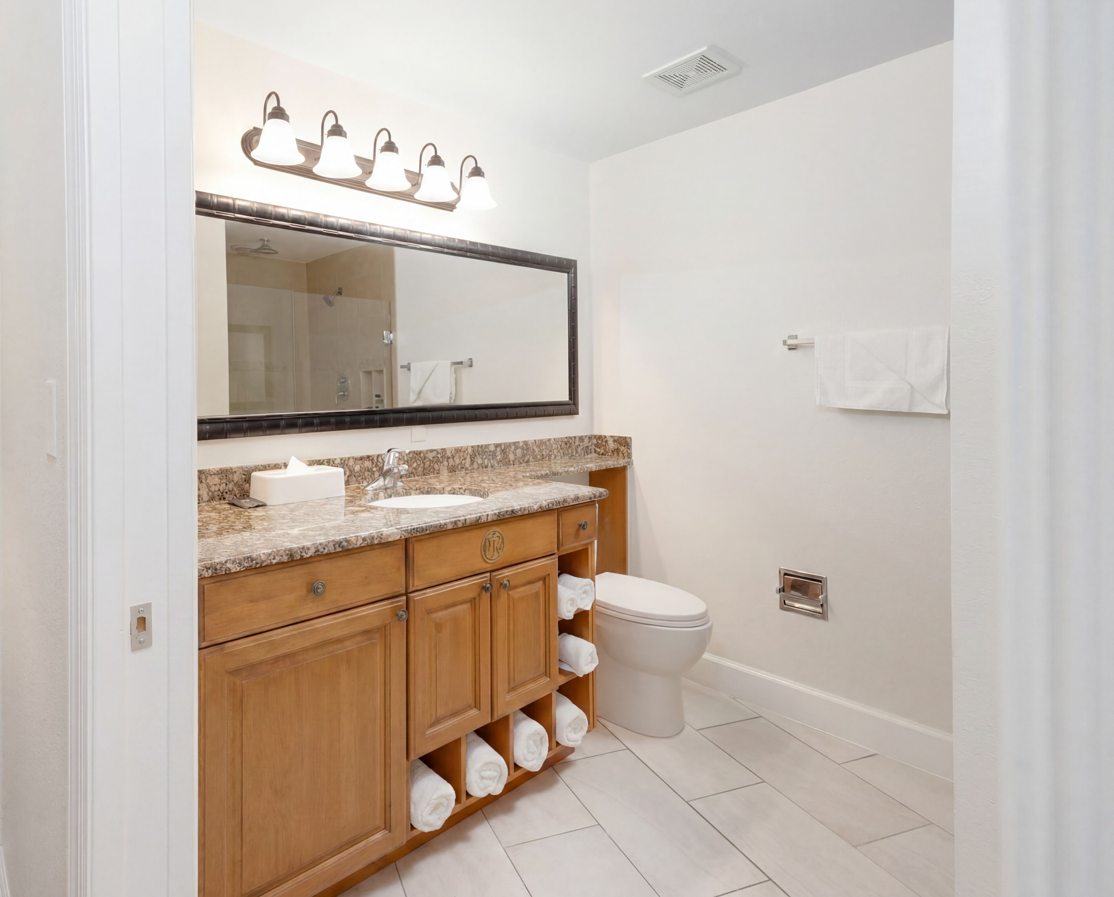 A bathroom with a large mirror, a sink, a toilet, and a towel rack.