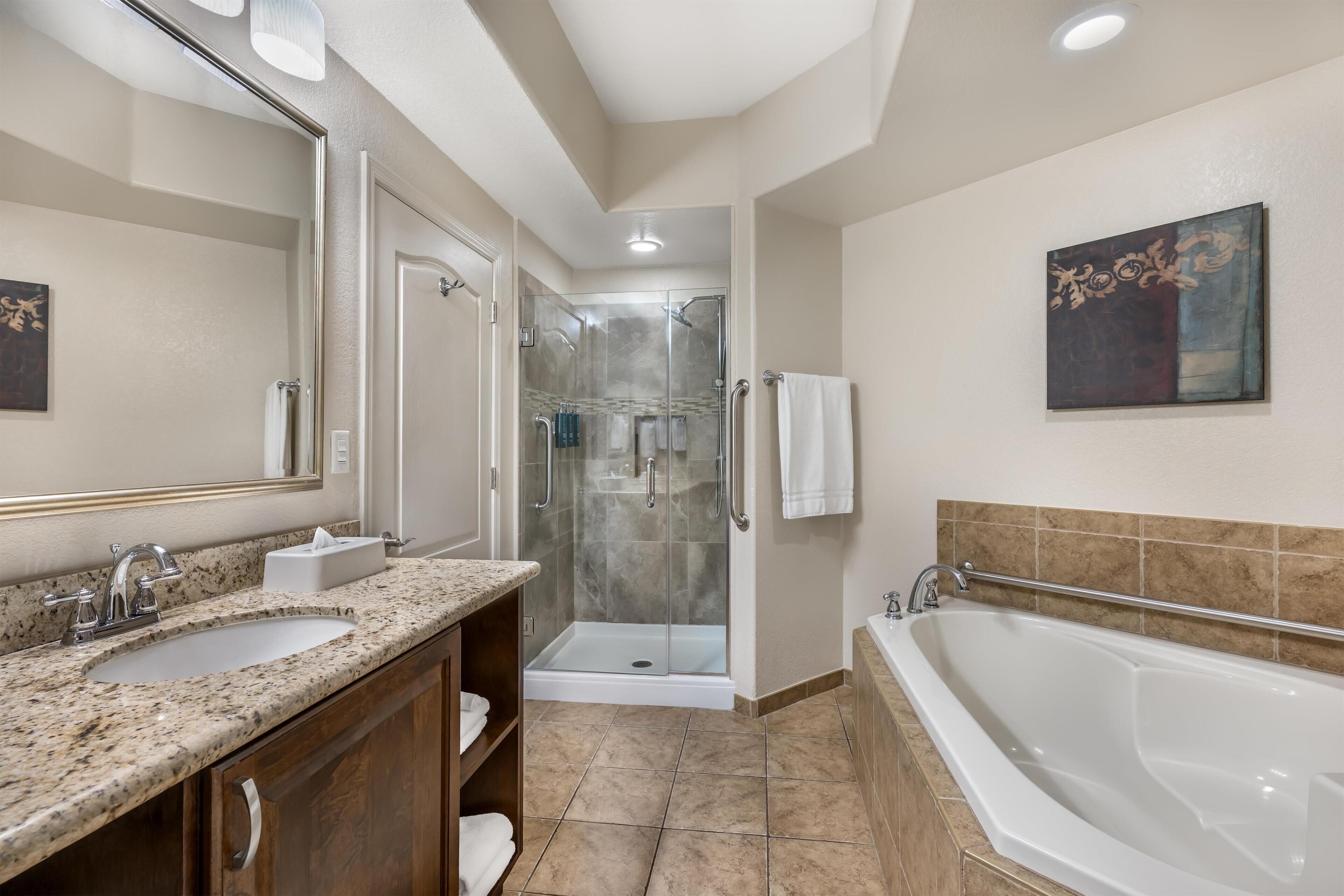 Une salle de bain moderne avec un grand lavabo, une baignoire, une douche à l’italienne et un miroir.